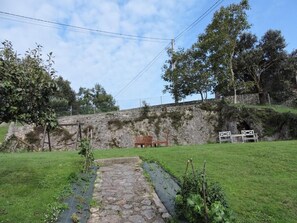 A stone wall, a grassy area, and a wooden bench. - Casa Pancho (Llanes)