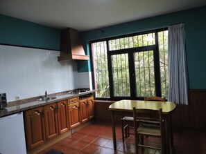 A kitchen with a window, a table, and chairs. - Casa Pancho (Llanes)