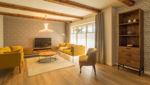 A modern living room with a fireplace, yellow sofas, a round coffee table, and a wooden bookshelf. - KajüteSiebenZwo - Holidays in a thatched house (St.Peter-Ording)