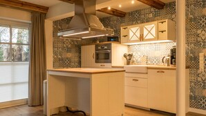 A kitchen with a central island, built-in oven, and patterned backsplash. - KajüteSiebenZwo - Holidays in a thatched house (St.Peter-Ording)
