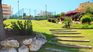 A landscaped garden with a wooden pathway, rocks, and various plants. - High Standard Apartment with Pool - UHC SALOU VILLA FAMILY COMPLEX 241 (Salou)