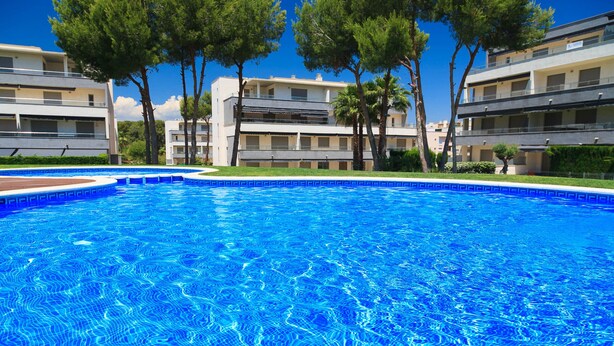 A swimming pool with clear blue water, surrounded by trees and modern buildings. - High Standard Apartment with Pool - UHC SALOU VILLA FAMILY COMPLEX 241 (Salou)