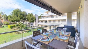 A balcony with a table set for dining, overlooking a garden and buildings. - High Standard Apartment with Pool - UHC SALOU VILLA FAMILY COMPLEX 241 (Salou)