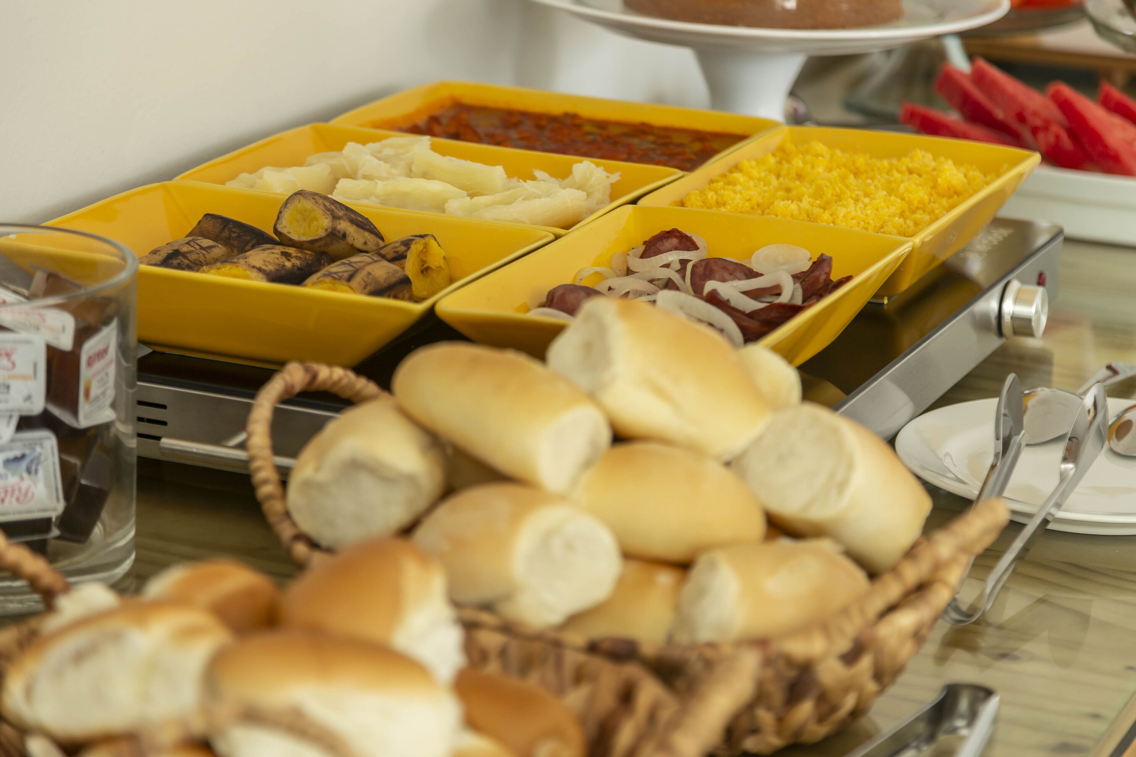 A buffet table with various food items in yellow bowls, including meats, cheeses, and vegetables.