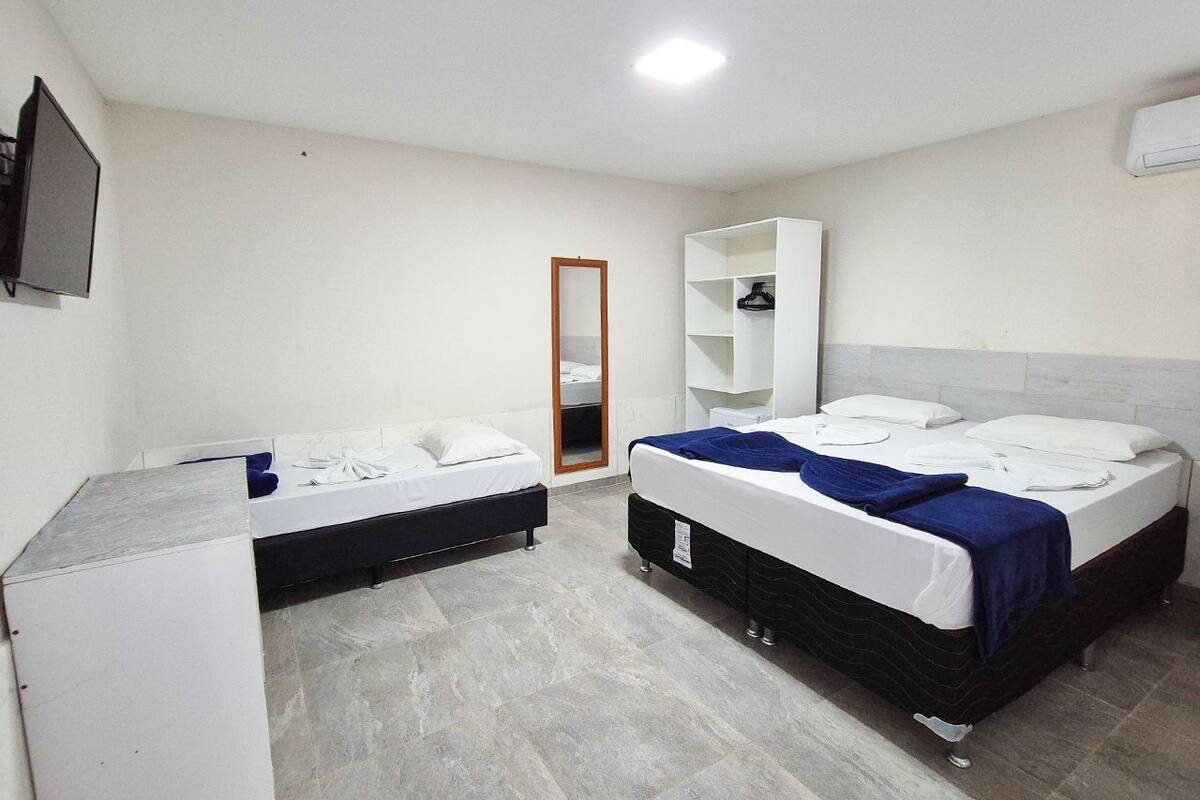 A room with two beds, a wardrobe, a mirror, and a television.