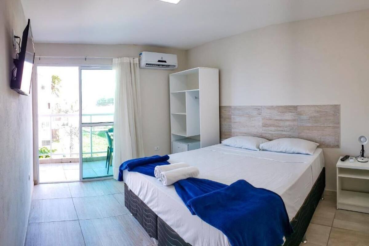 A hotel room with a bed, a wardrobe, a desk, and a balcony.
