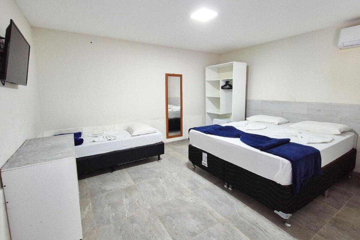 A hotel room with two beds, a wardrobe, a mirror, and a television.