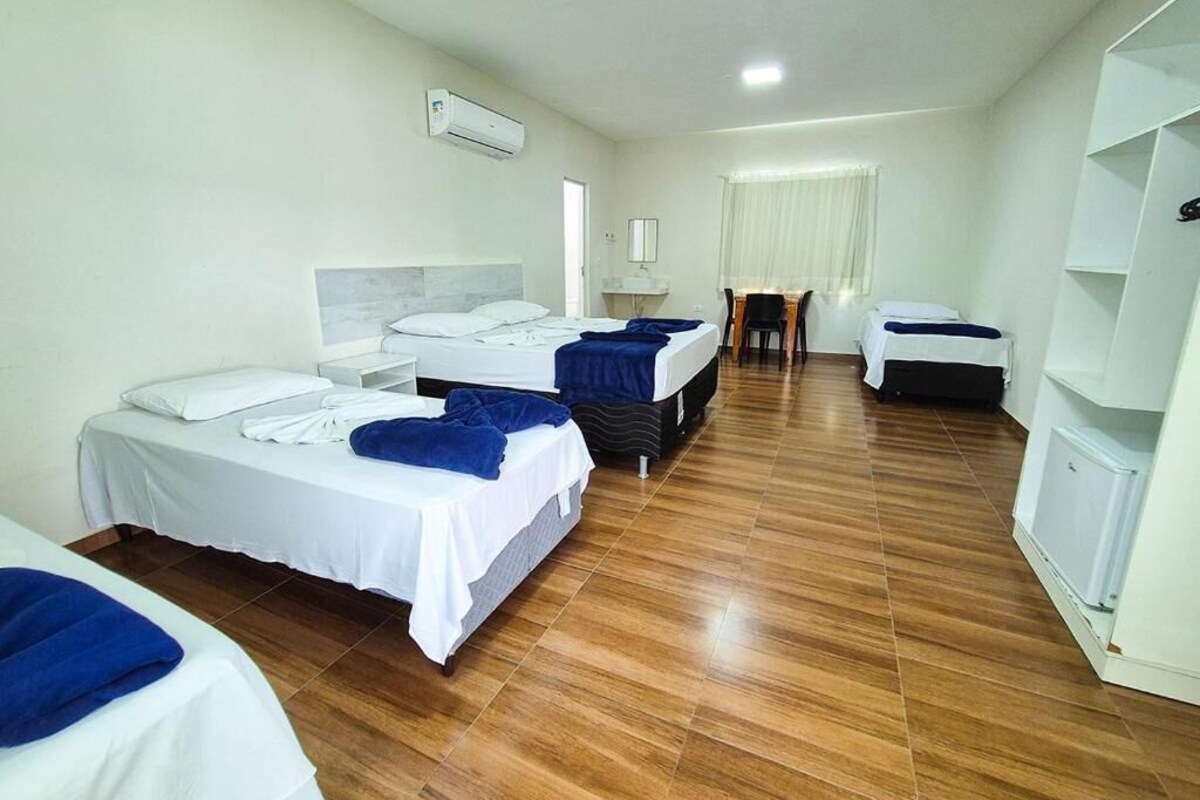 A hotel room with two beds, a desk, a chair, and a white wardrobe.