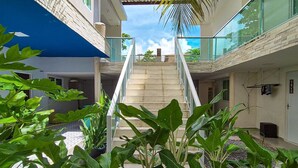 A modern building with a central staircase, surrounded by lush greenery and a clear sky. - Maresia Unique (Ipojuca)