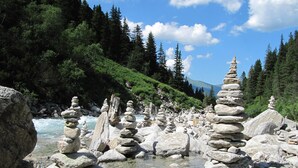 Paisaje natural con un río, agua cristalina y pilas de rocas.