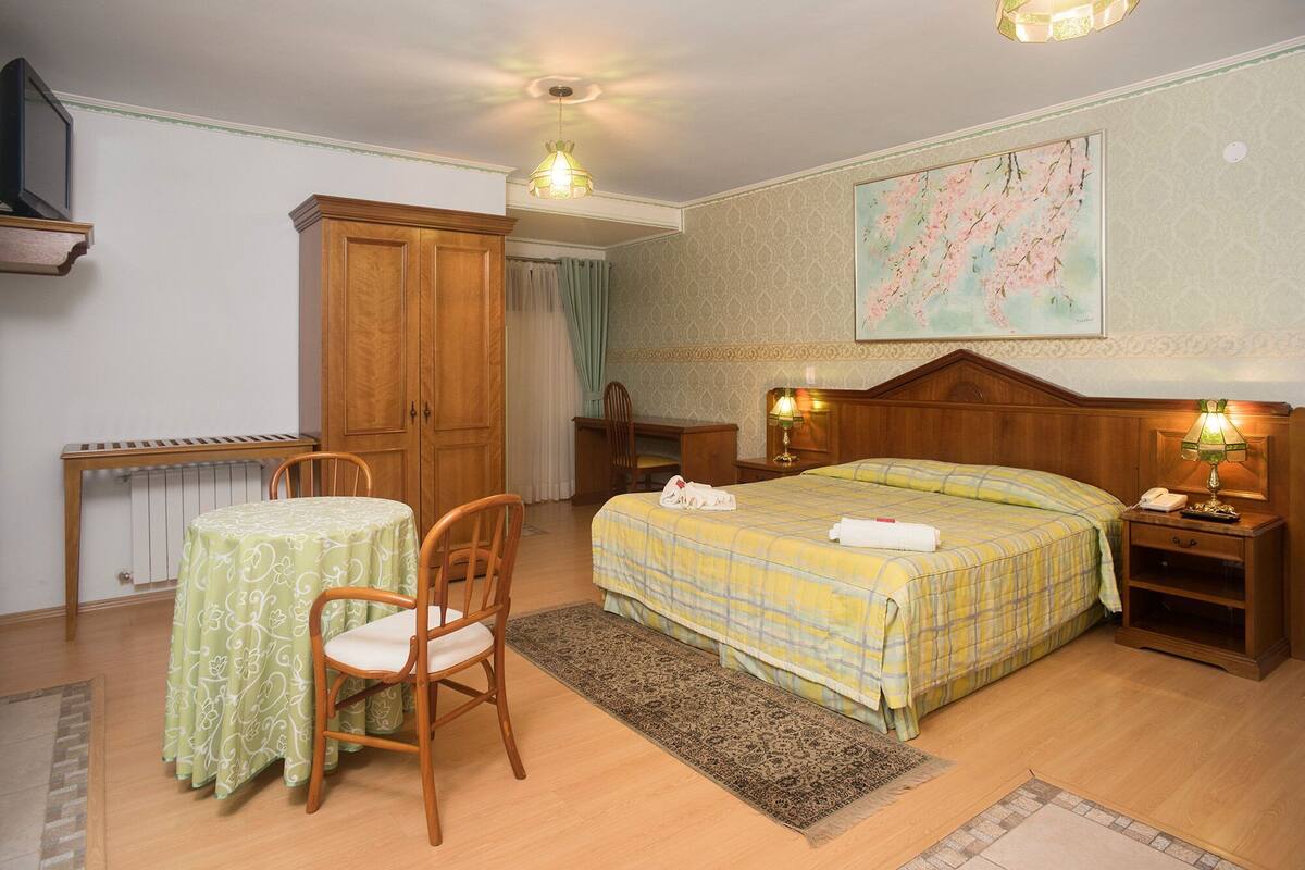 Een keurig ingerichte slaapkamer met een bed, een bureau, een stoel en een tafel.
