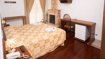 Habitación de hotel con cama, escritorio, silla, televisor, chimenea y refrigerador.