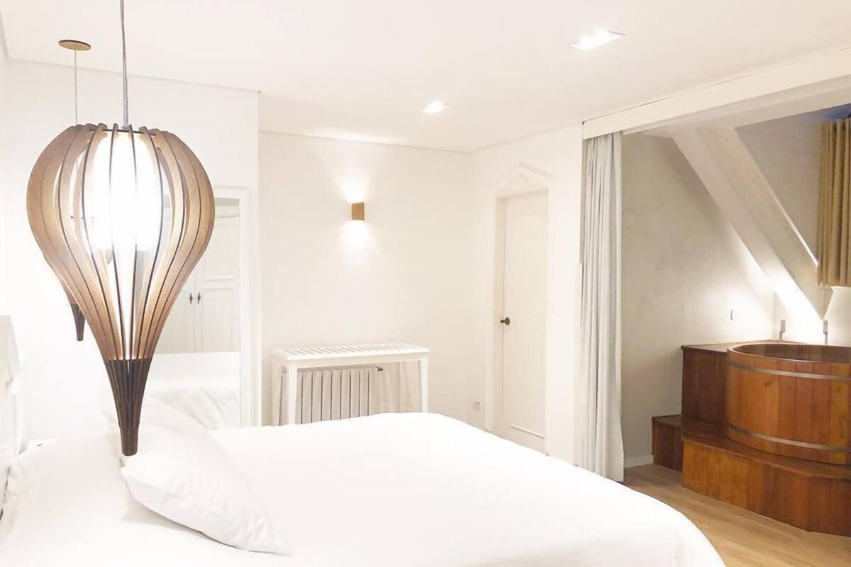 Een slaapkamer met een groot bed, een bijzondere hanglamp, een radiator en een houten vat.