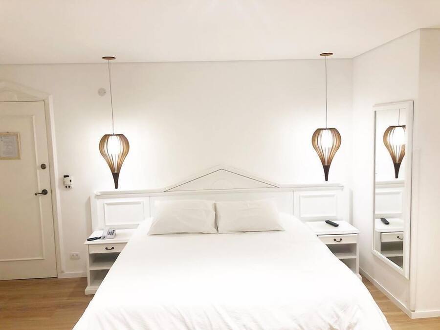 Un dormitorio con una cama grande, mesitas de noche y un espejo.