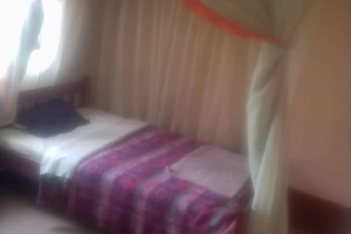 Una habitación con una cama, una ventana con cortinas y una colcha.