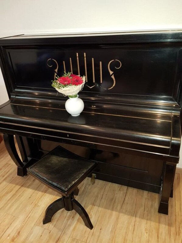 A black piano with a white vase of red flowers on the music stand.