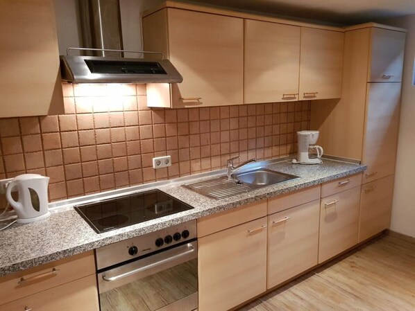 A kitchen with a stove, sink, and cabinets.