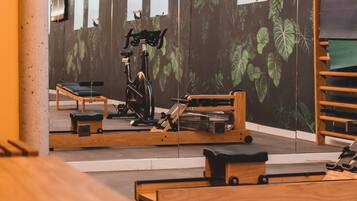 A gym with exercise equipment, wooden benches, and a wall-mounted TV.