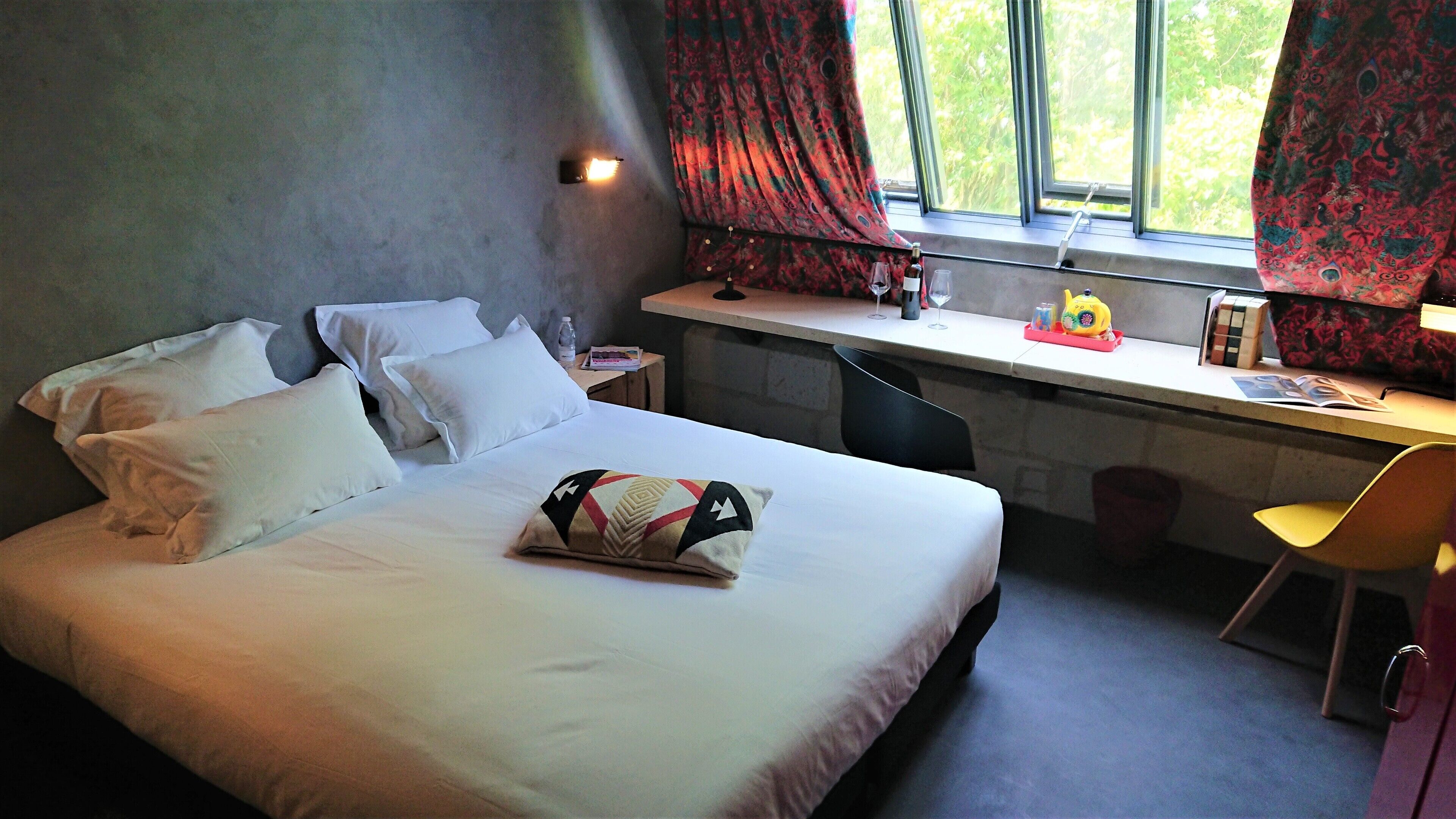 Una camera d'albergo con un letto, una scrivania e una sedia.