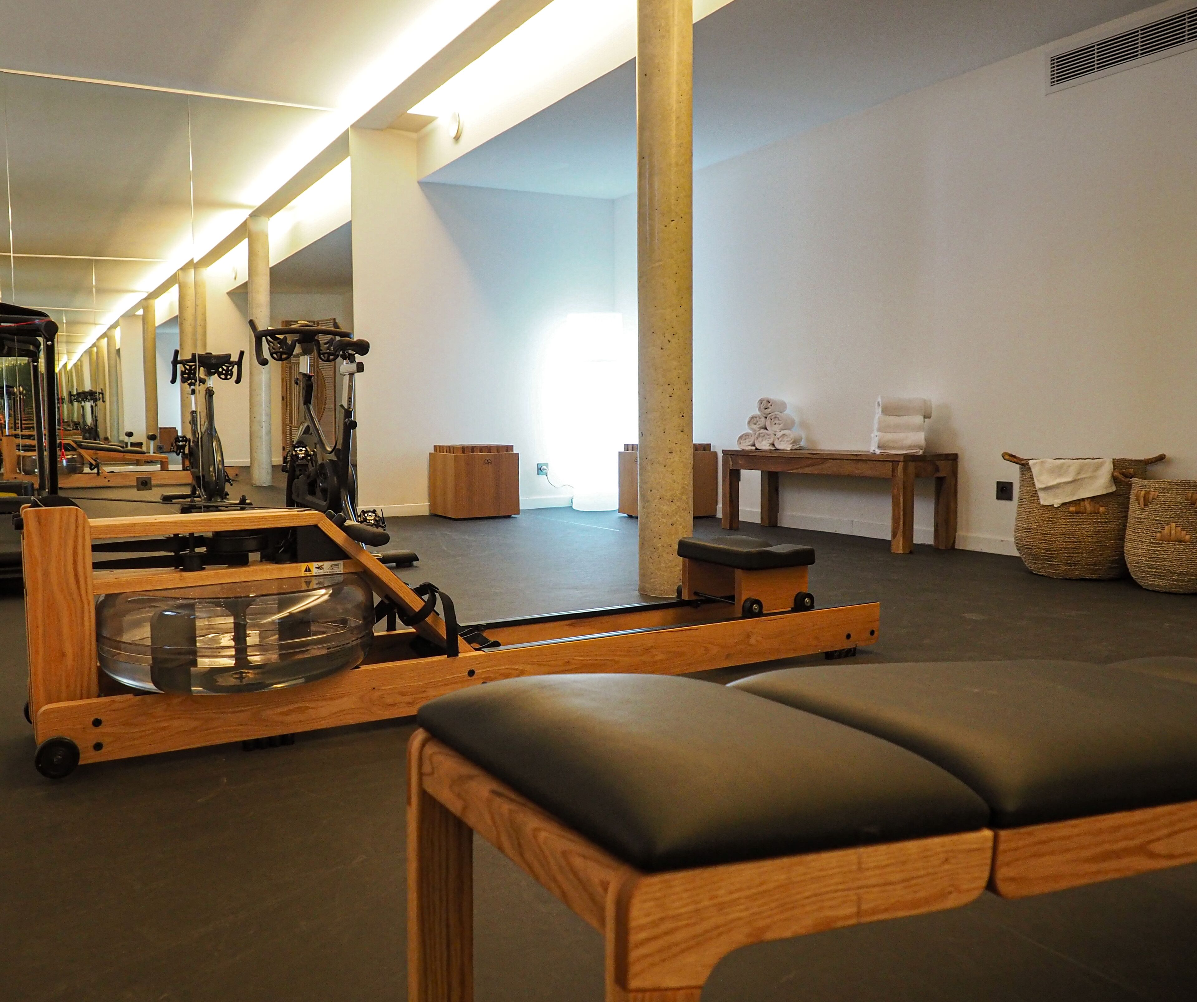 A gym with exercise equipment, a bench, and a table with towels.