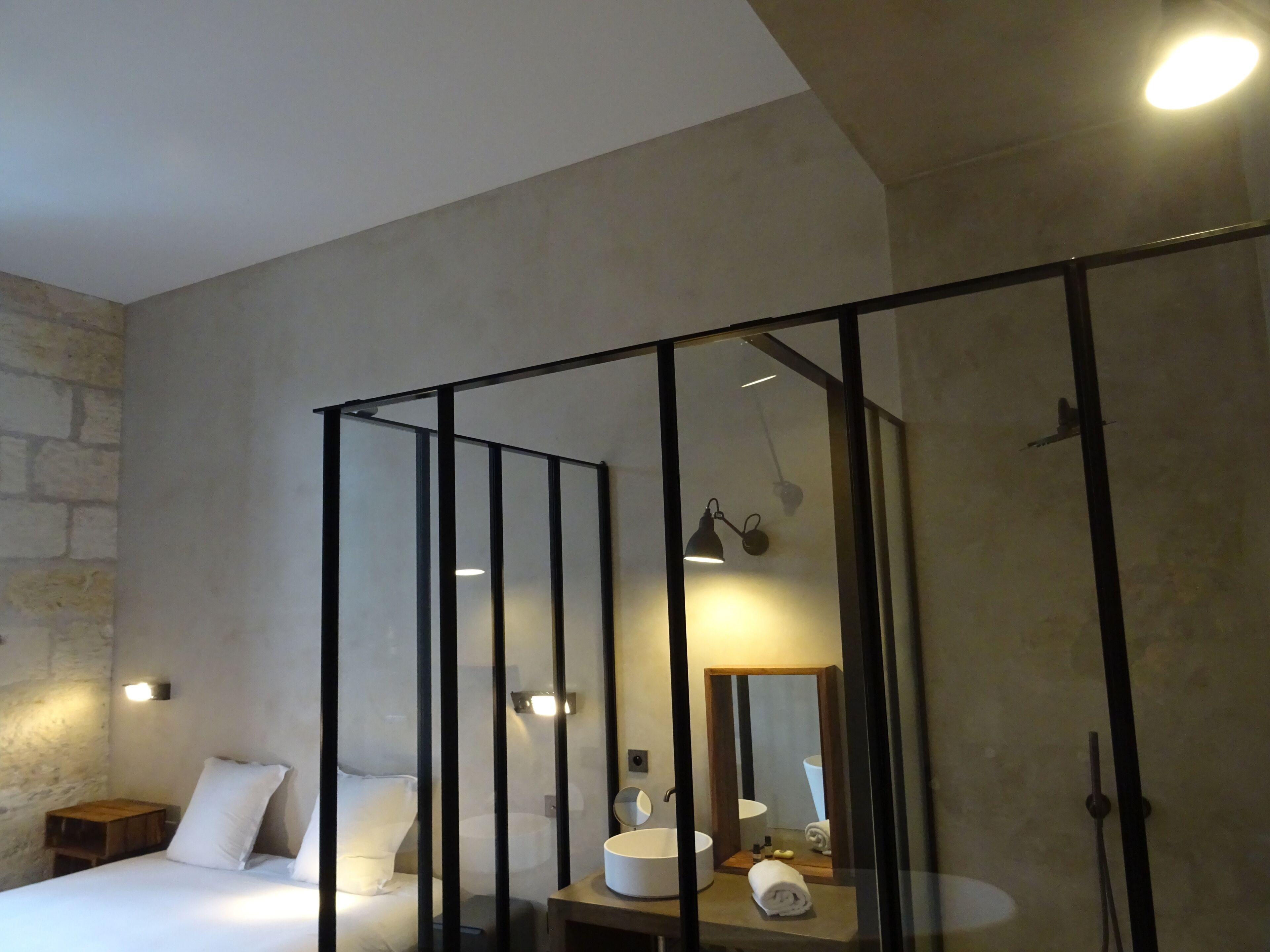 Une chambre à coucher moderne, avec un lit, une table de chevet et une salle de bain équipée d’un lavabo et d’un miroir.