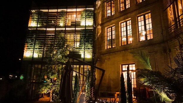 Un edificio de varios pisos con fachada de vidrio moderna y revestimiento de piedra tradicional.