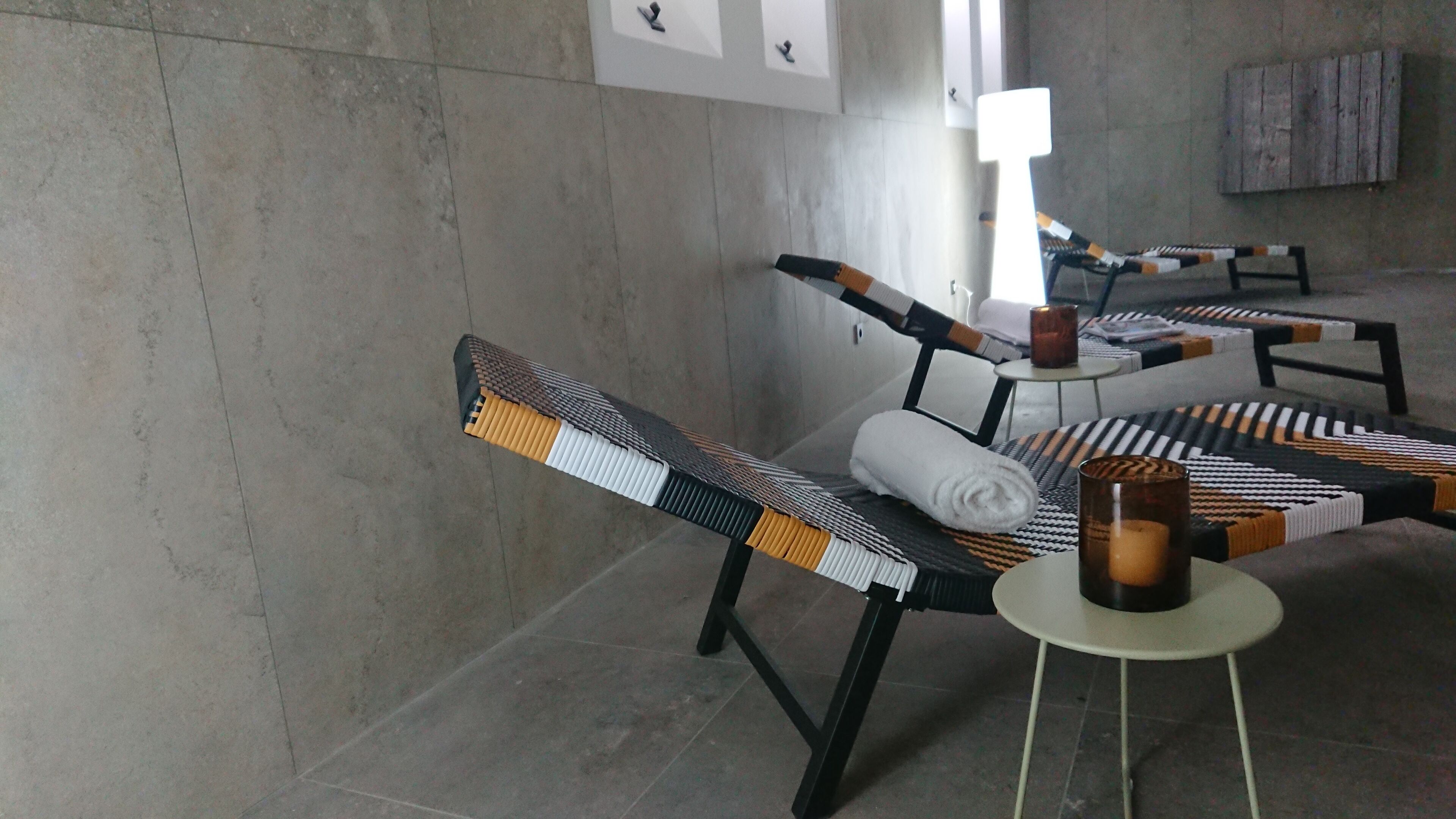 Una habitación de hotel moderna con una zona de estar que incluye sillas tejidas y una pequeña mesa redonda con una vela.