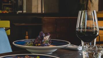 A dining table with plates of food, a glass of red wine, and cutlery.