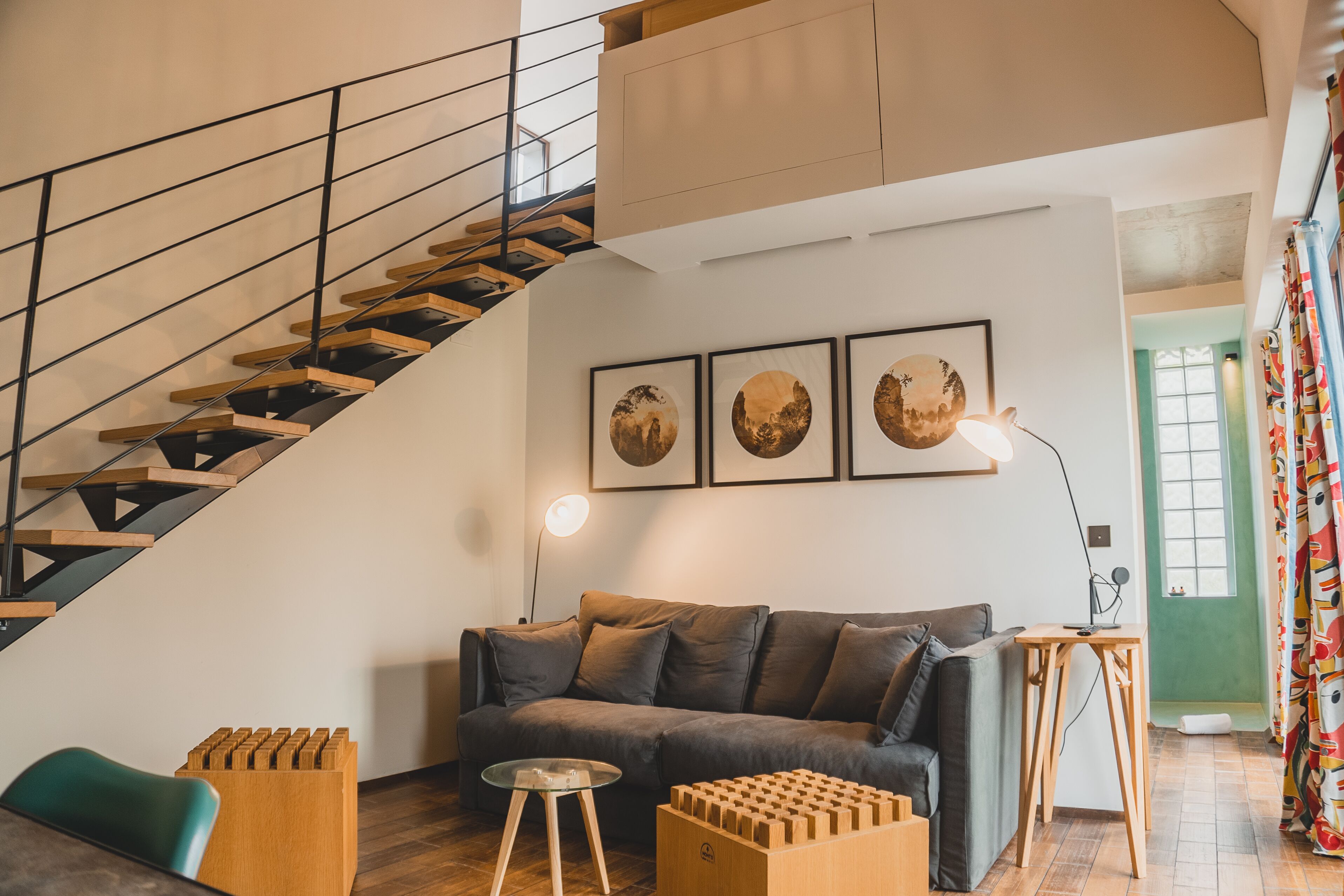 Een moderne woonkamer met een trap, een bank, een salontafel en een lamp.