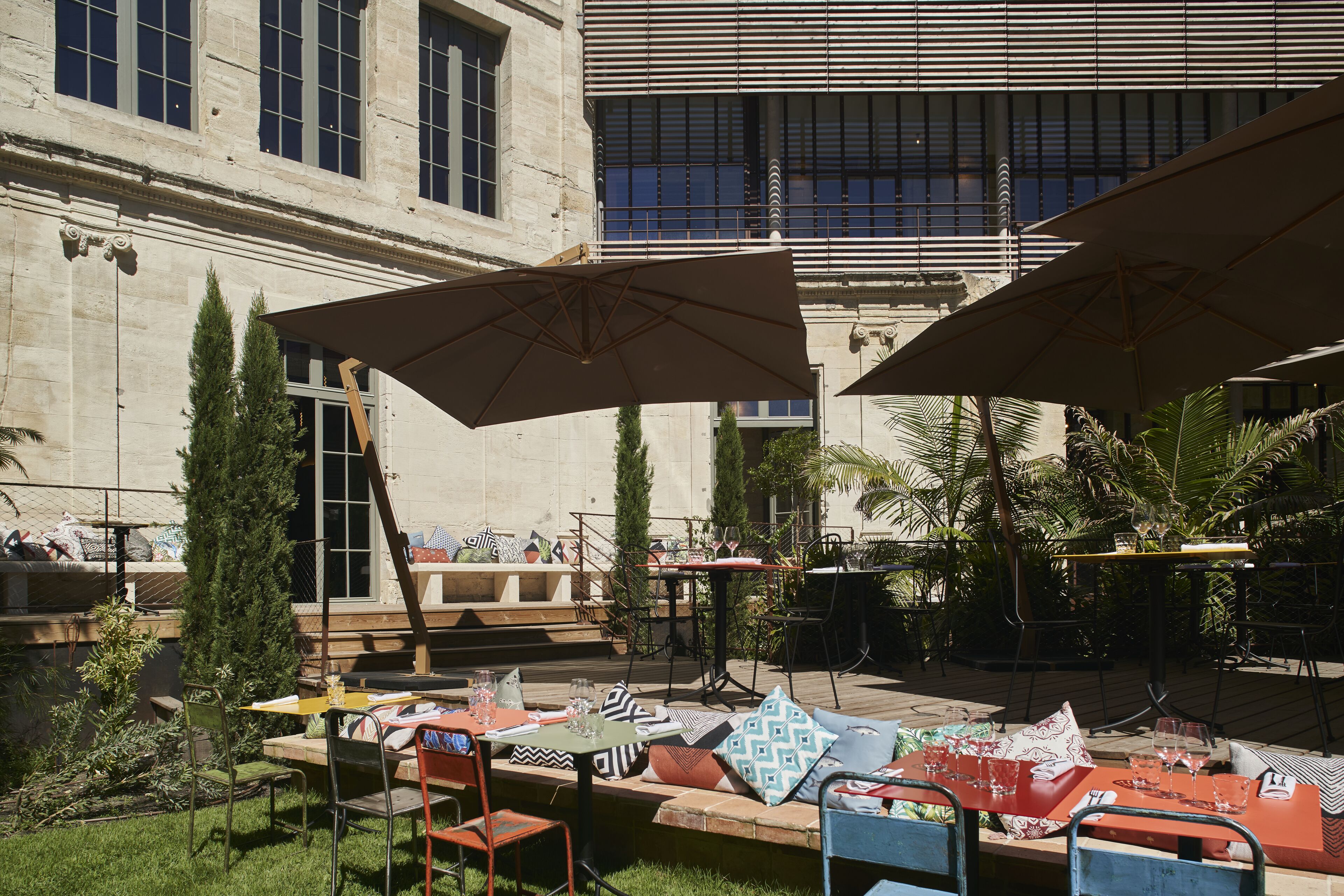 An outdoor seating area with tables and chairs, umbrellas, and a building in the background.