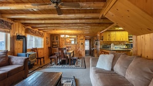A cozy log cabin interior with a living room, dining area, and kitchen.