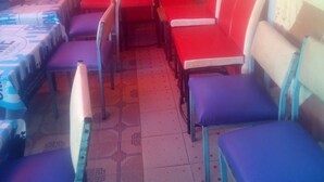 A restaurant with red and blue seating, a patterned floor, and a sign on the wall. - Sokoni Guest House (Nairobi)