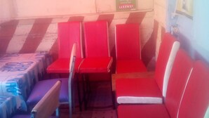 A waiting area with red seating, a table with a sign, and a wall with a sign. - Sokoni Guest House (Nairobi)