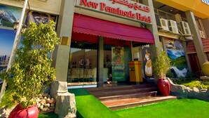 A hotel with a yellow facade, large windows, and a red awning. - New Penninsula Hotel (Dubai)