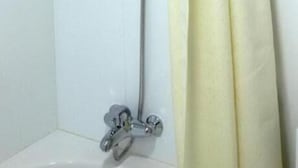 A shower with a handheld showerhead, a wall-mounted control panel, and a floor-mounted faucet. - New Penninsula Hotel (Dubai)