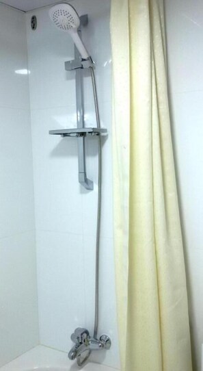 A shower with a handheld showerhead, a wall-mounted control panel, and a floor-mounted faucet. - New Penninsula Hotel (Dubai)