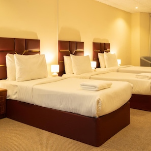 A hotel room with two beds, each with a headboard, bedside tables, and lamps. - New Penninsula Hotel (Dubai)