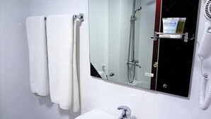 A bathroom with a white sink, a mirror, and a hairdryer on a shelf. - New Penninsula Hotel (Dubai)