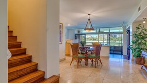 A spacious dining area with a wooden staircase, a hanging light fixture, and a view of the outdoors. - Beautiful updates--everything new! Golf course views!  Huge 2/2 K. Royal #A301 (Lahaina)