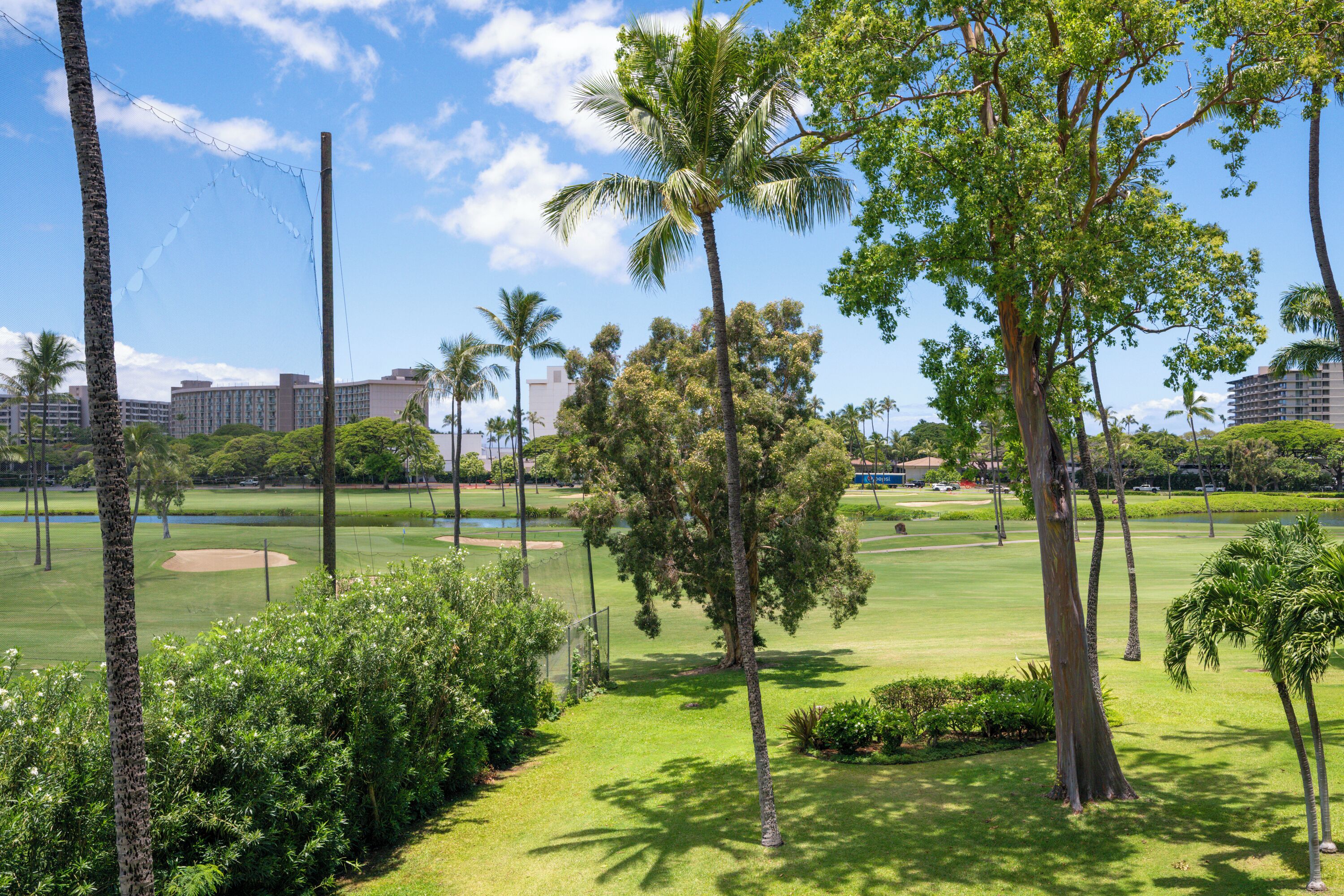 Un campo da golf con alberi, una recinzione e edifici sullo sfondo.