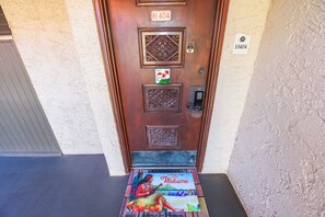 A wooden door with a number plate, a welcome mat, and a small sign.