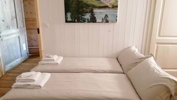 Ein Schlafzimmer mit zwei Betten, Holzboden, einem Gemälde einer Berglandschaft und einer weißen Tür.
