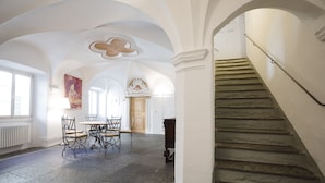 A spacious room with a dining area, a staircase, and a large arched doorway. - Cà del Borgo, Rooms & Suites (Poschiavo)