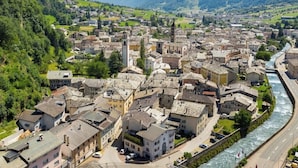 A town with historic buildings, a river, and mountains in the background. - Cà del Borgo, Rooms & Suites (Poschiavo)