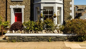 A corner house with a stone facade, a red door, and a bay window.
