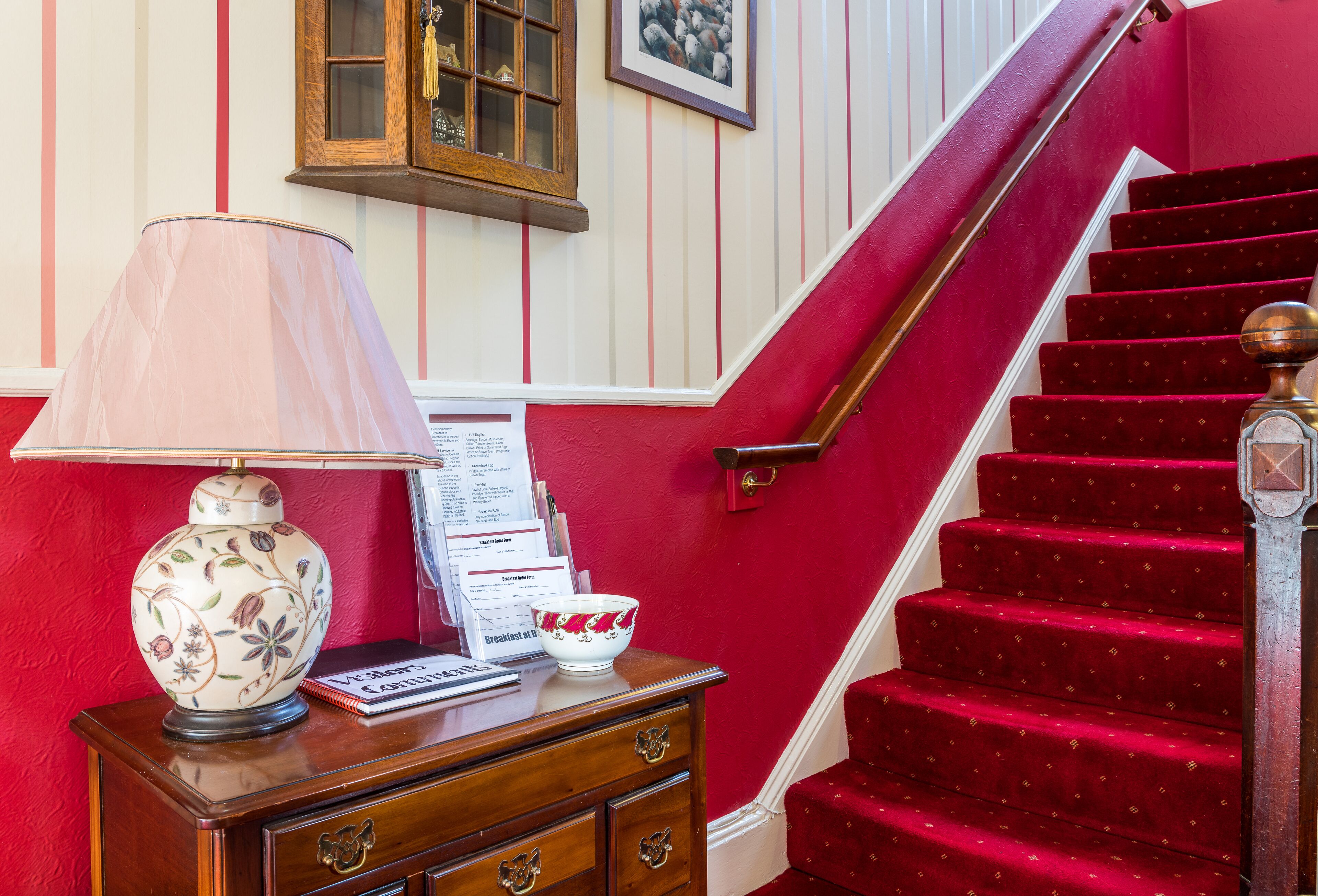 A staircase with red carpeted steps and a wooden handrail.
