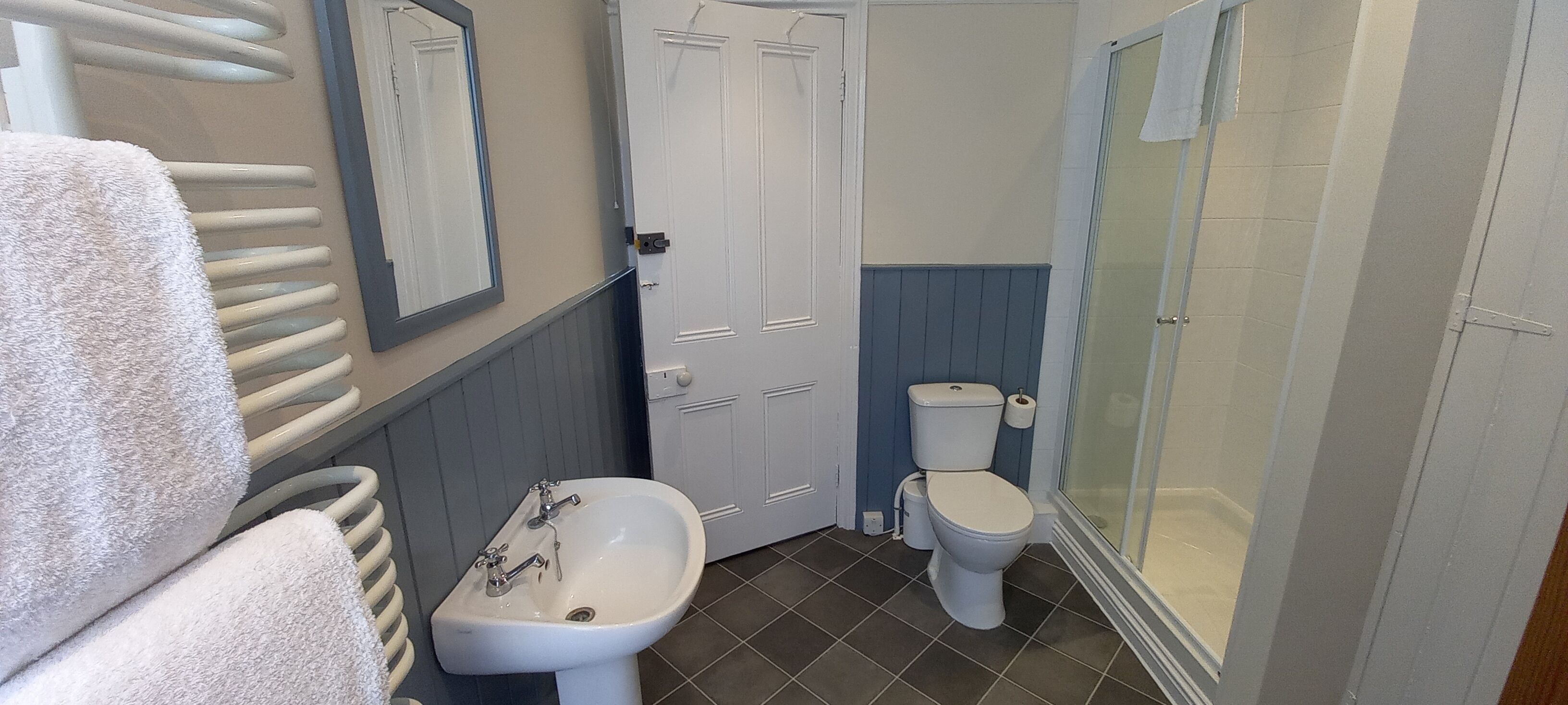 Et badeværelse med vask, toilet og brusebad.