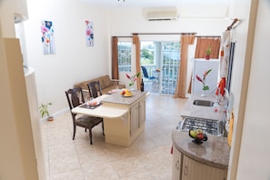 A kitchen with a dining area, a gas stove, a sink, and a view of the outdoors. - Affordable, Majestic, St. Lucia Jazz and Carnival, Bay View Apartment (Castries)