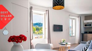 Een moderne woonkamer met een eethoek, een aan de muur bevestigde televisie en een balkon met een prachtig uitzicht.