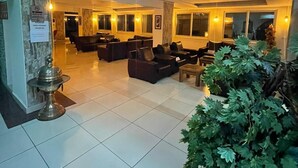 A spacious lobby with multiple seating areas, a large potted plant, and a clock on the wall. - Denizhan Otel (Antalya)